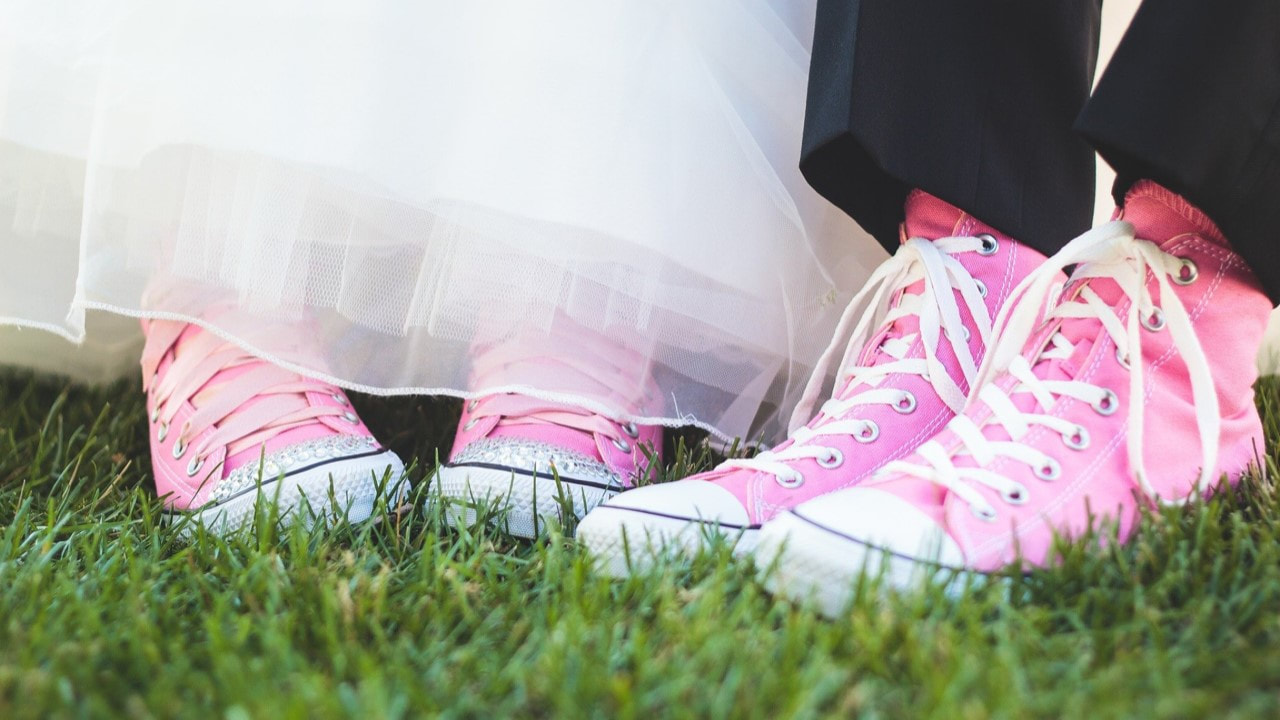 the feet of a bride and groom wearing pink converse